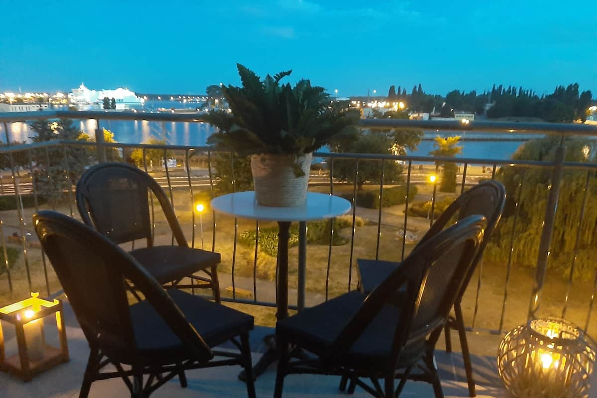 Un balcón con dos sillas, una mesa, una planta en maceta y un farol.