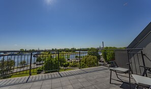 A balcony with a view of a river, a bridge, and a distant tower. - Baltic Apartments - Apartamenty Bałtyk (Swinoujscie)