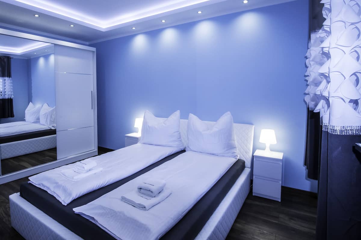 Una habitación de hotel con una cama grande, un armario, una mesita de noche y un espejo.