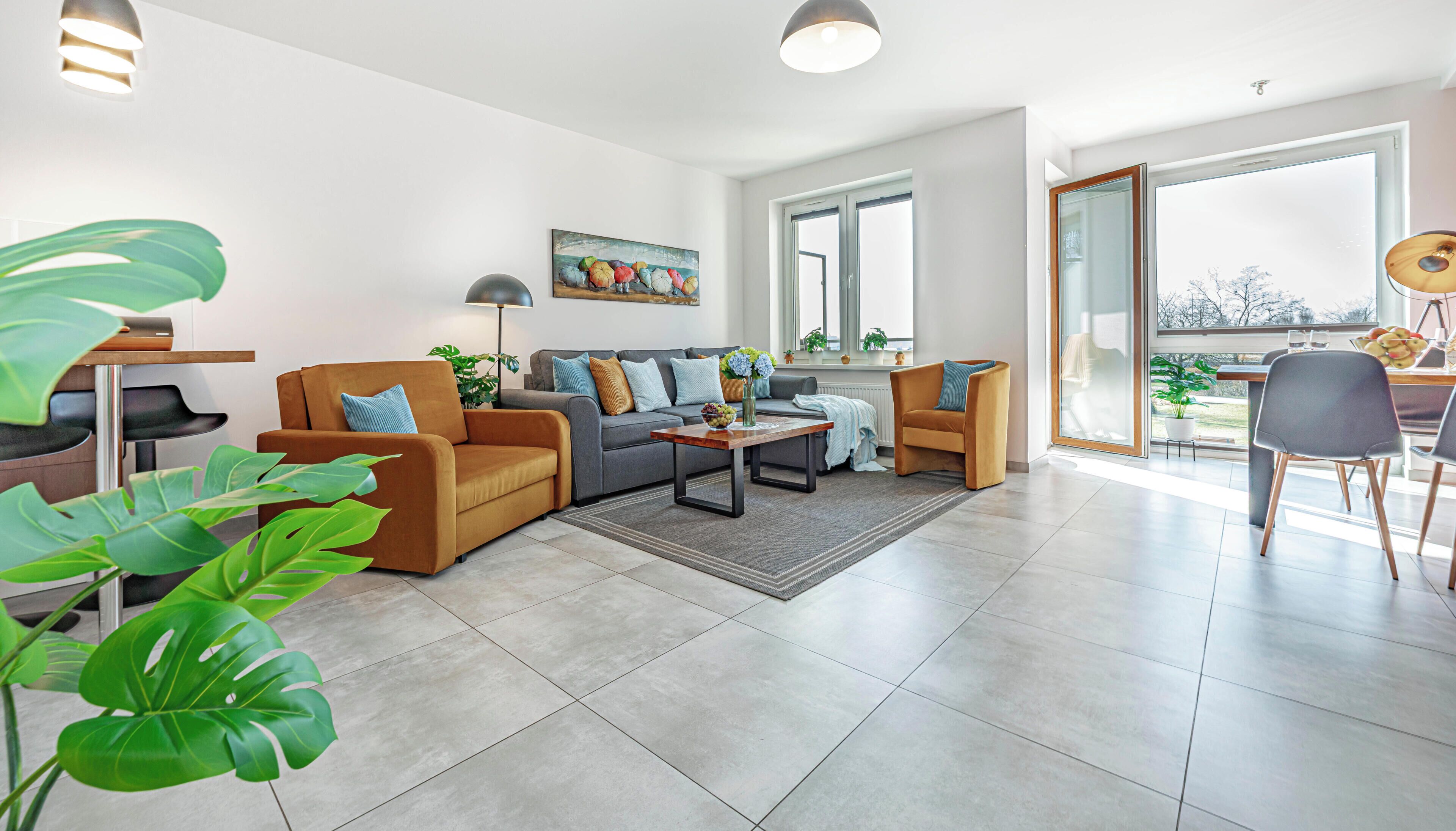 A modern living room with a sofa, armchairs, a coffee table, and a dining area with chairs.