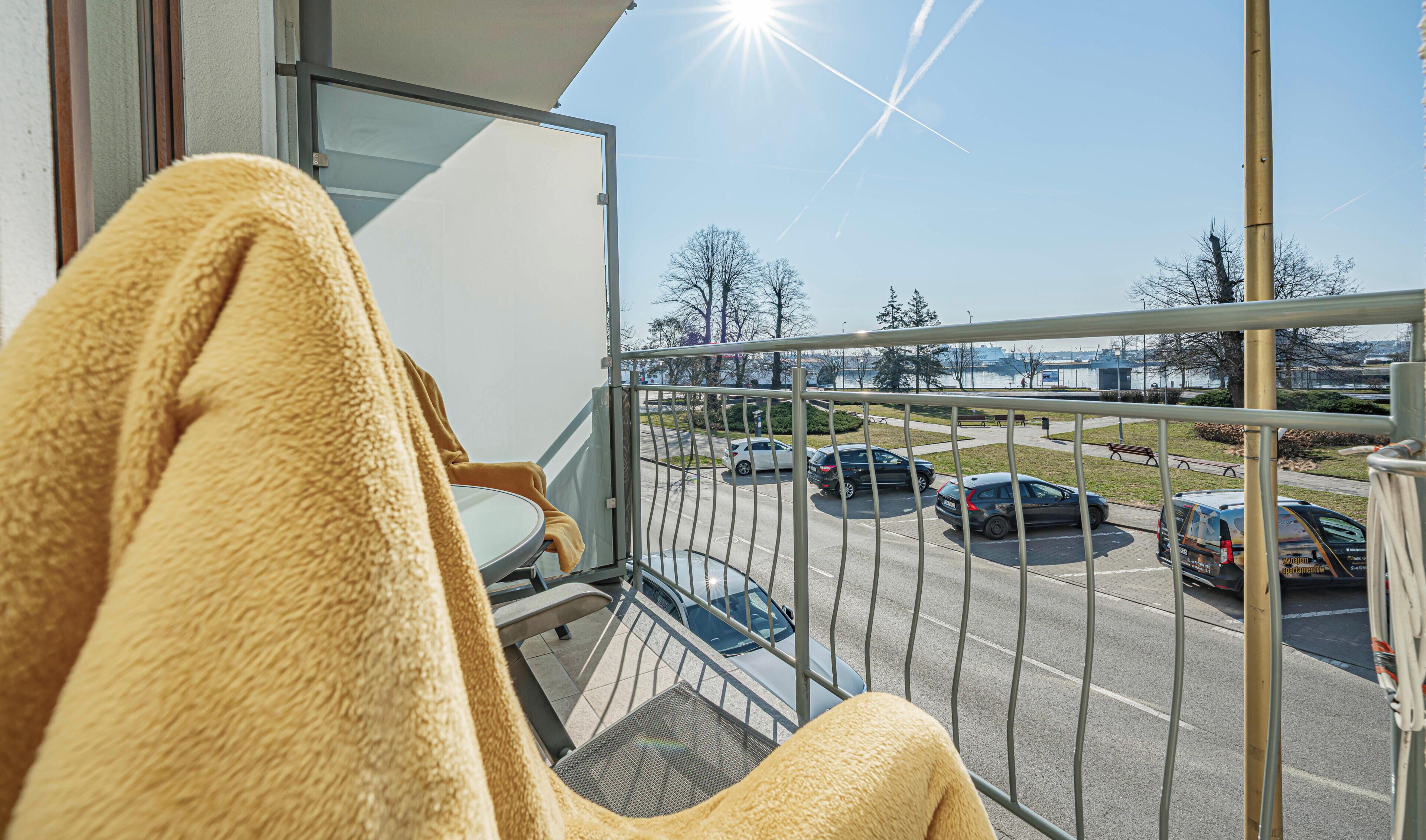 A balcony with a view of a parking lot and a body of water.