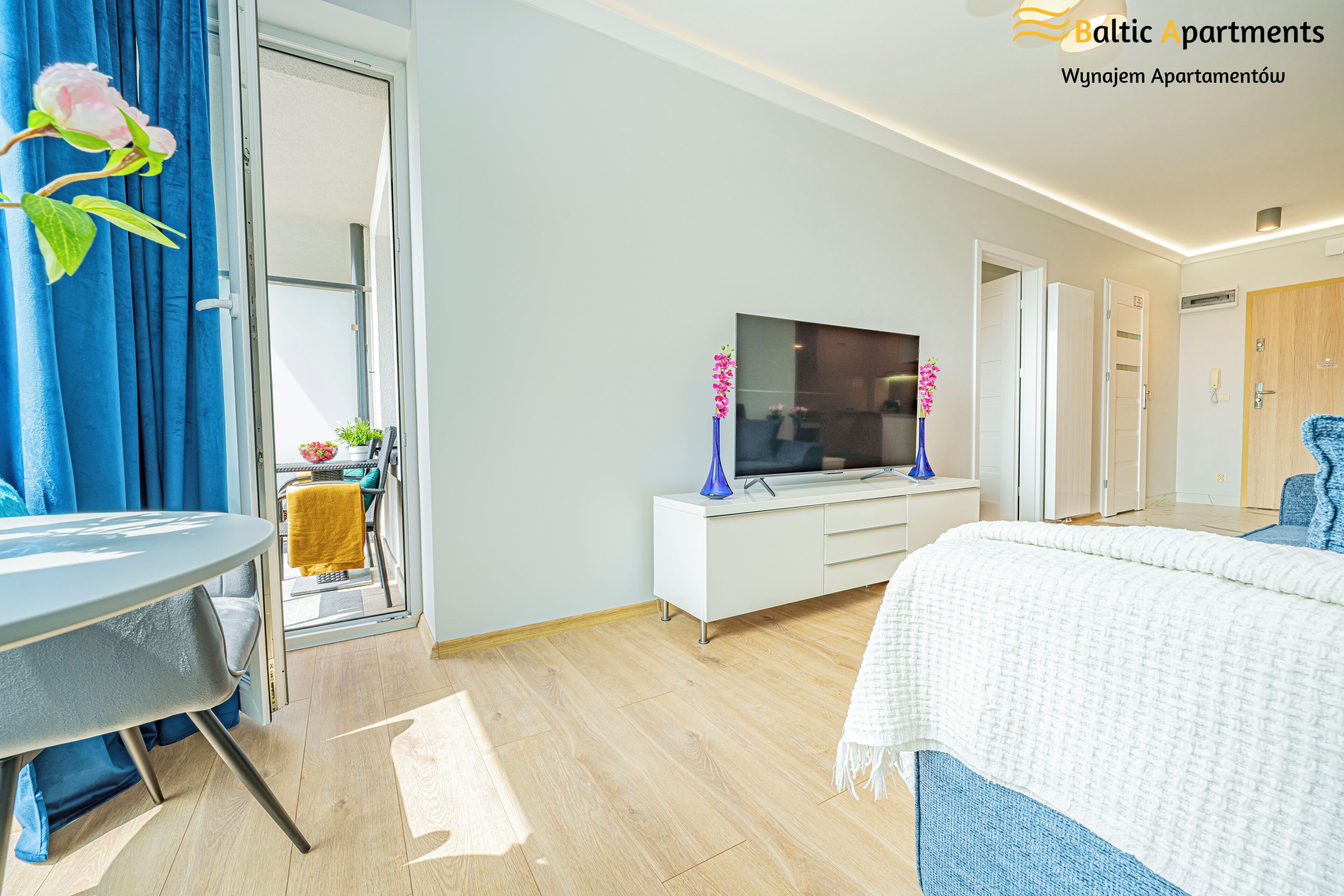 Ein modernes Hotelzimmer mit Bett, Fernseher, Schreibtisch und einem Fenster mit Vorhängen.