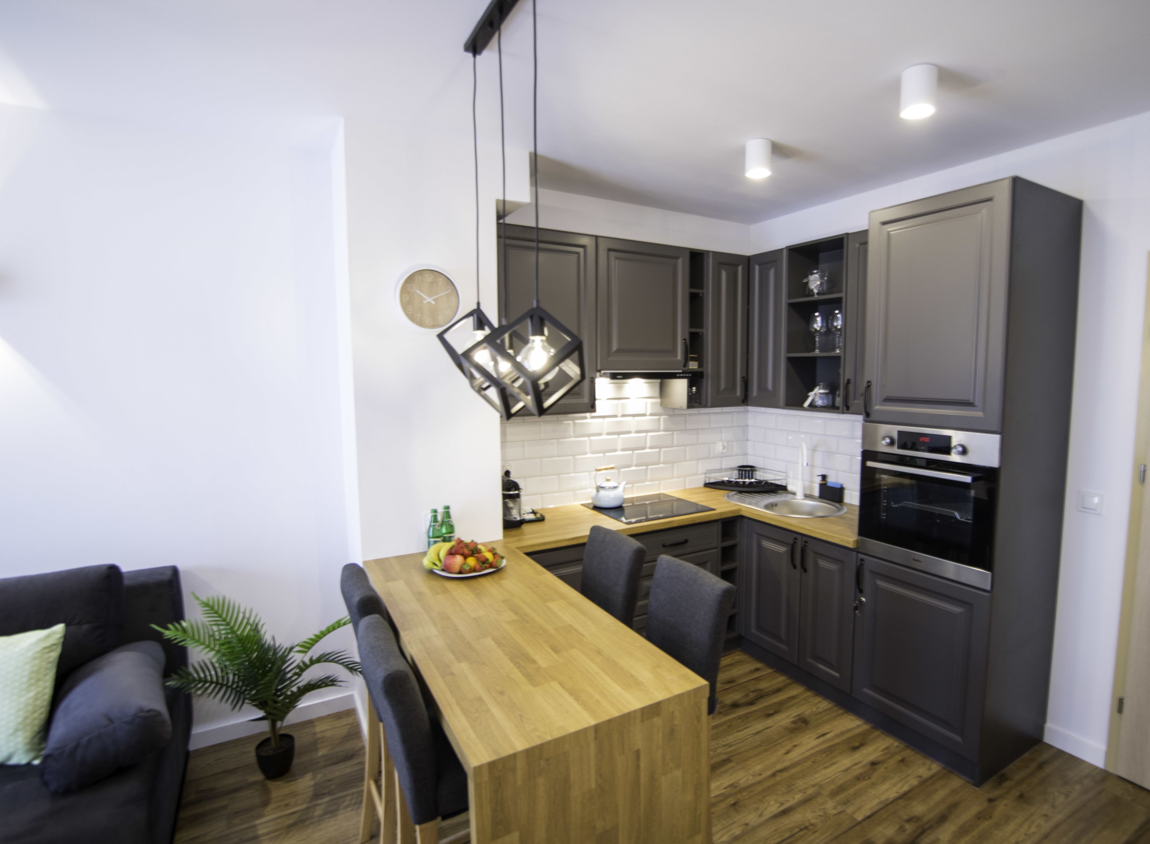 A modern kitchen with grey cabinets, a wooden countertop, and a built-in oven.