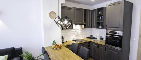 A modern kitchen with grey cabinets, a wooden countertop, and a built-in oven.