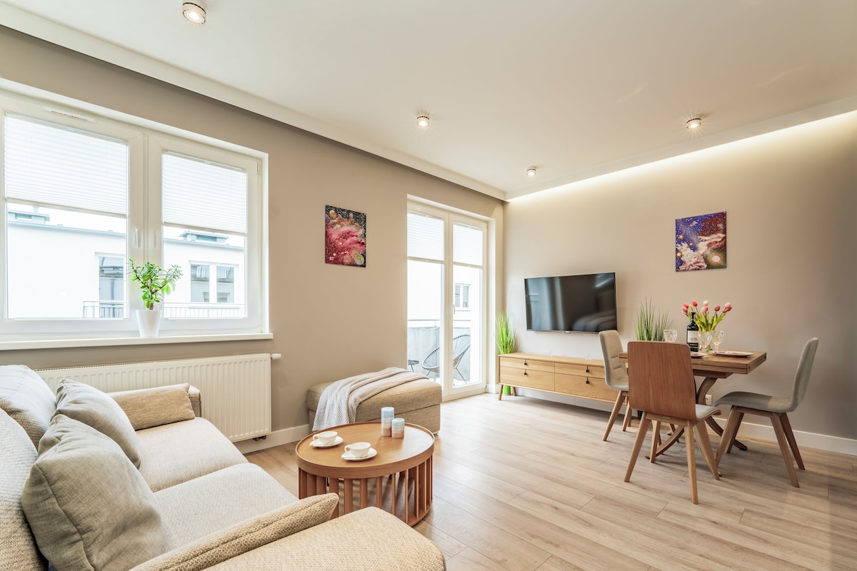 Un salon moderne comprenant un canapé, une table à manger et des chaises, un téléviseur et des œuvres d’art accrochées aux murs.
