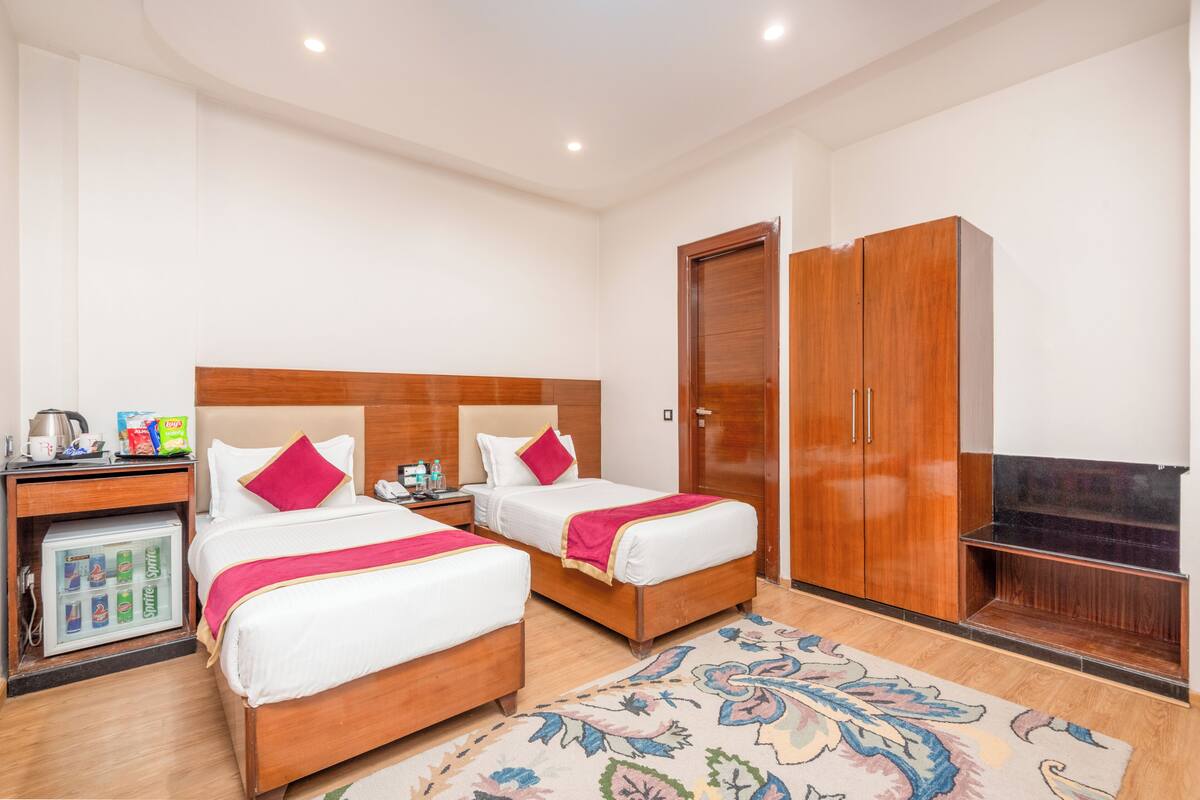 A hotel room with two beds, a minibar, a television, and a wardrobe.