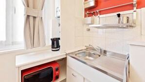 A modern kitchen with a stainless steel sink, a kettle, and a red microwave. - Cosy Nest Isola District Heart (Milan)