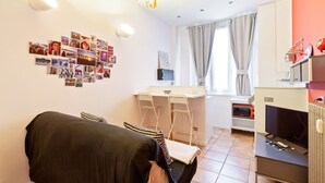 A compact living space with a sofa, a dining area, and a kitchenette. - Cosy Nest Isola District Heart (Milan)