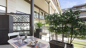 A dining area with a table set for two, a potted plant, and a view of the street. - Elegant Loft with balcony (Milan)