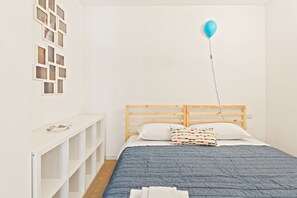 A bedroom with a wooden headboard, a blue quilted bedspread, and a single blue balloon tied to the headboard. - Elegant Loft with balcony (Milan)