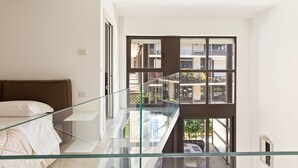 A modern bedroom with a glass balcony, a bed, and a view of the outside building. - Elegant Loft with balcony (Milan)