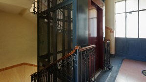 Una escalera con barandilla de metal y pasamanos de madera, que lleva a una puerta con panel de vidrio.