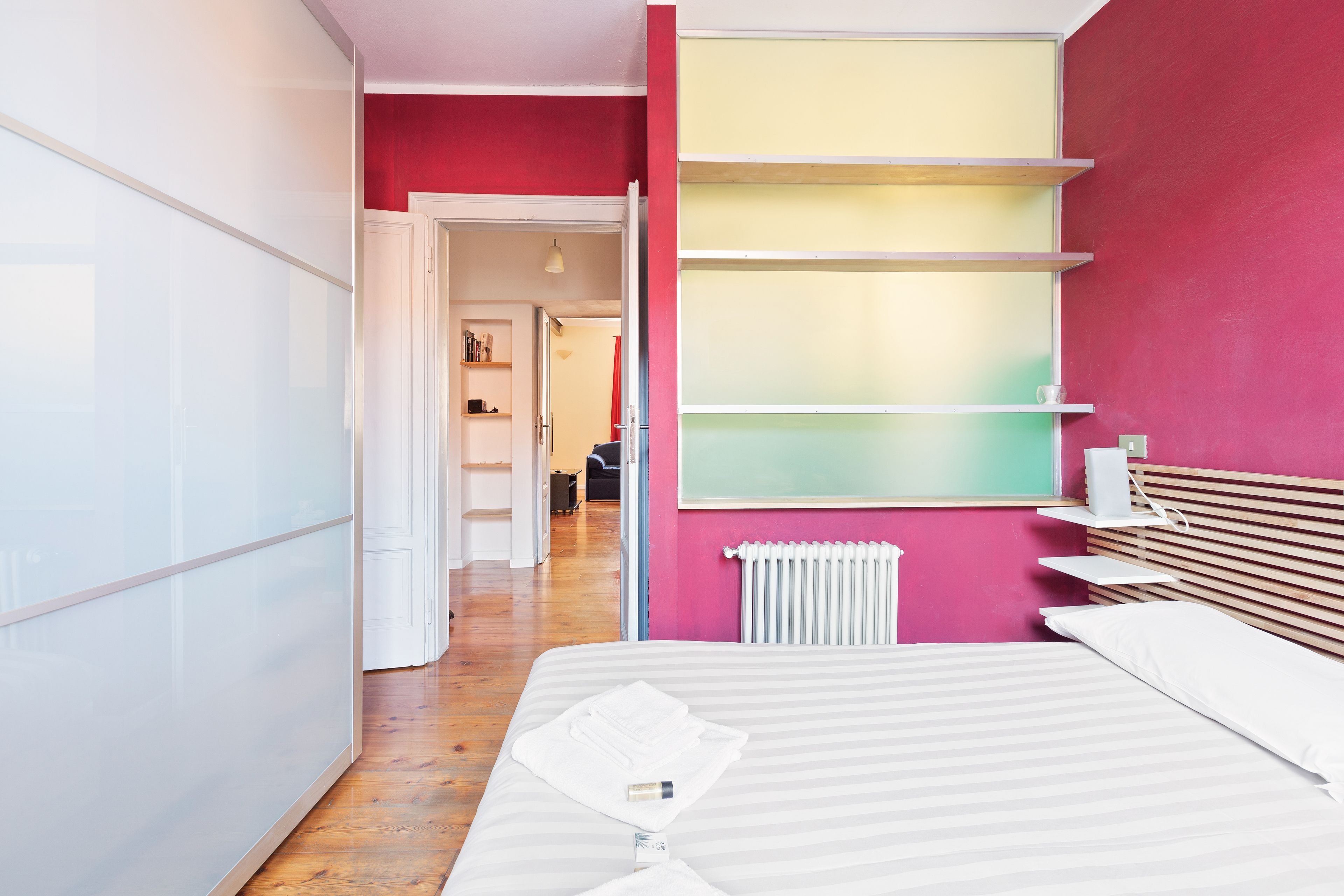 A modern bedroom with a bed, a radiator, and a shelf unit.