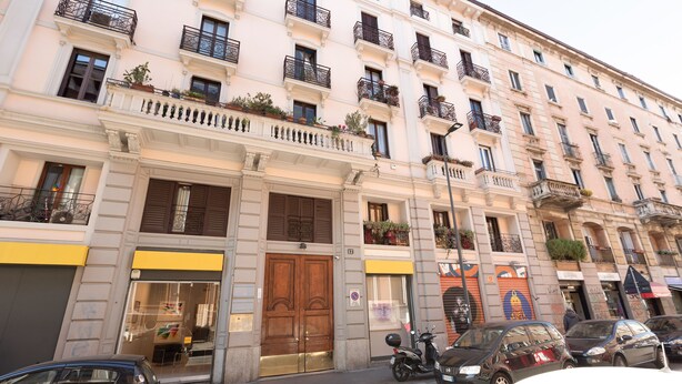 Un edificio de varios pisos con una tienda en la planta baja, una puerta de madera cerrada y una scooter estacionada.