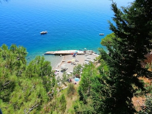A coastal beach with clear blue waters, boats, and a pier. - Villa Ruzmarina (Omis)