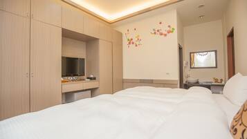 Hotelkamer met een bed, een bureau met een computer, een spiegel en een wand met bloemdecoraties.