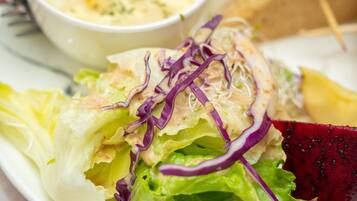 Een salade met gemengde bladgroenten en paarse kool, vergezeld van een dressing.