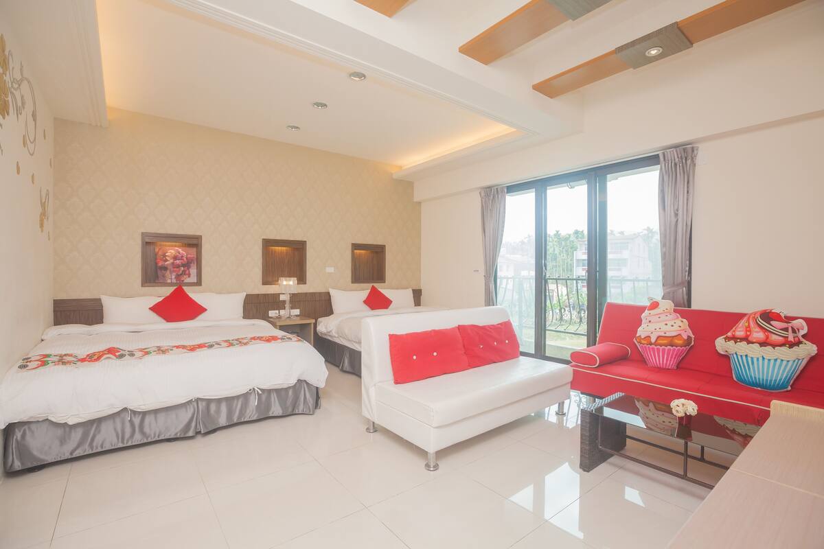 Habitación de hotel con dos camas, un sofá y un balcón con vistas.