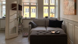 A modern living room with a sofa, a coffee table, and a large window with blinds. - Best Stay Copenhagen Ny Adelgade 7 2nd (Copenhagen)