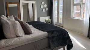 A bedroom with a large bed, a mirror, a radiator, and a view of the outside through a window. - Best Stay Copenhagen Ny Adelgade 7 2nd (Copenhagen)