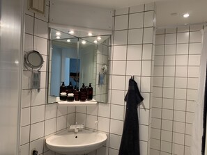 A bathroom with a white sink, mirror, and tiled walls.