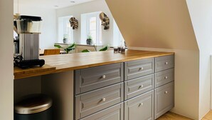 A kitchen with a wooden countertop, grey cabinets, and a coffee machine. - Best Stay Copenhagen Ny Adelgade 8-10 (Copenhagen)