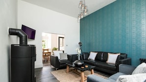 Una sala de estar moderna con un sofá negro, una mesa de centro y una chimenea.