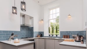 Una cocina moderna con armarios blancos, salpicadero de azulejos azules y electrodomésticos de acero inoxidable.