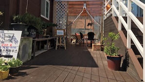 A guest house with a wooden deck, outdoor seating, and potted plants. - Hago Guest House (Tongyeong)