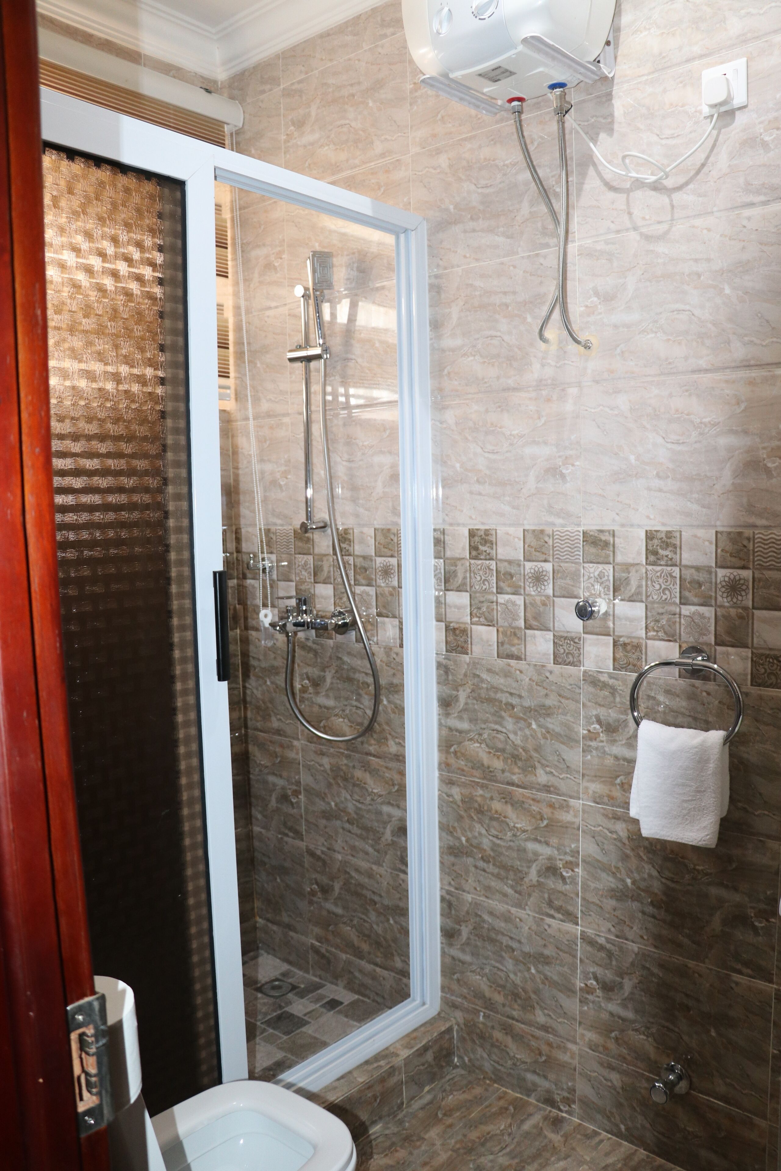 A modern bathroom with a glass-enclosed shower, a toilet, and a towel rack.