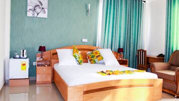 Une chambre d’hôtel avec un lit en bois, une table de chevet avec une lampe, une chaise et une petite table avec un téléphone et une lampe.