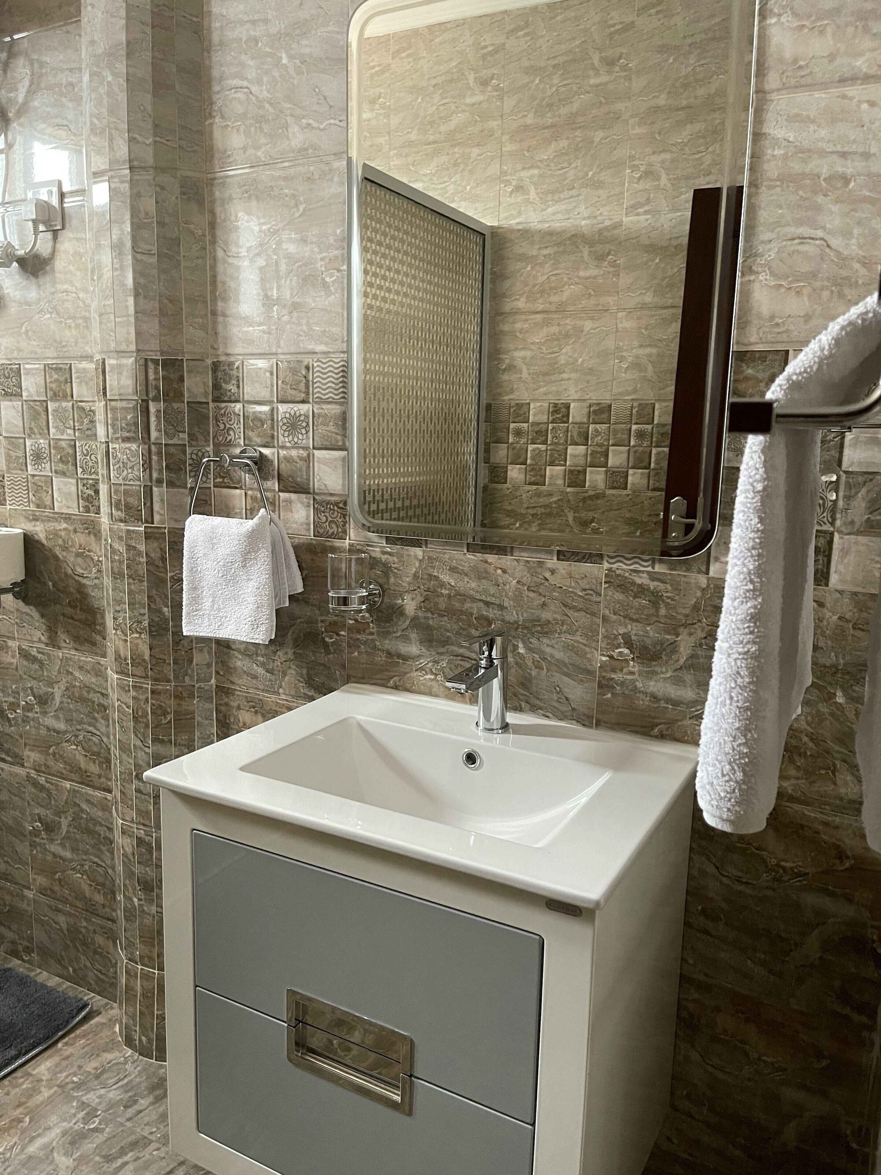 A bathroom with a white sink, a mirror, and a towel rack.