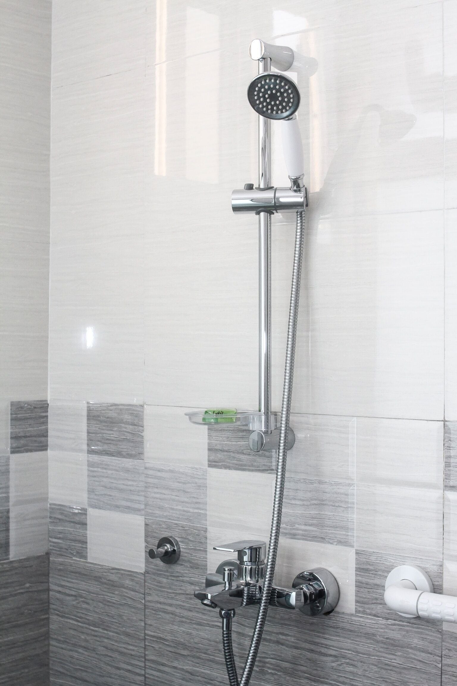 A shower with a handheld showerhead and a wall-mounted control valve.