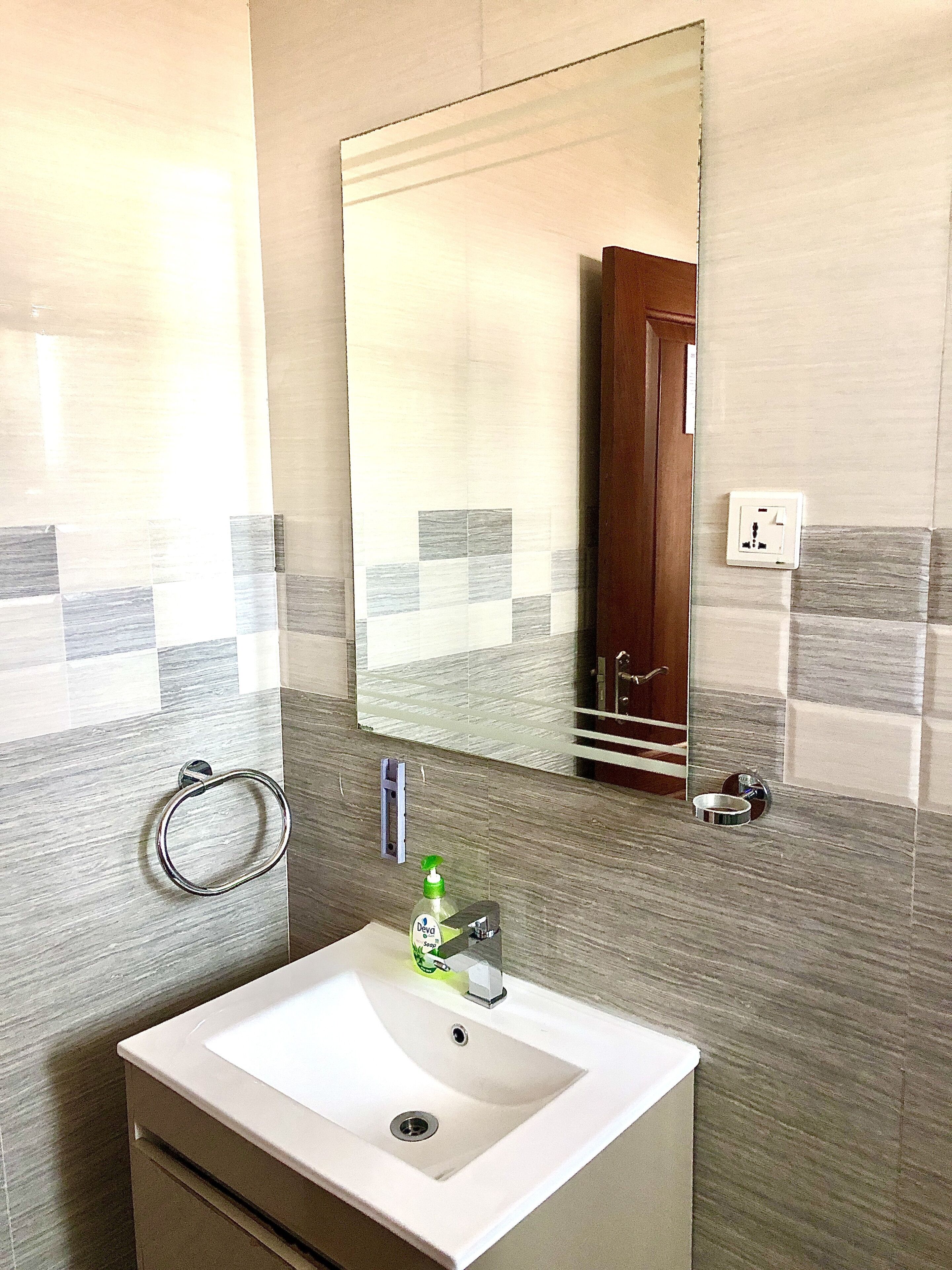 A bathroom with a white sink, a mirror, and a towel ring.