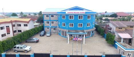 Un immeuble à plusieurs étages, doté d’une façade bleue et d’une enseigne indiquant « HÔTEL EXOTIC PALACE ».