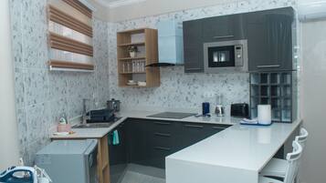 A modern kitchen with a central island, dark cabinets, a microwave, and a built-in oven.