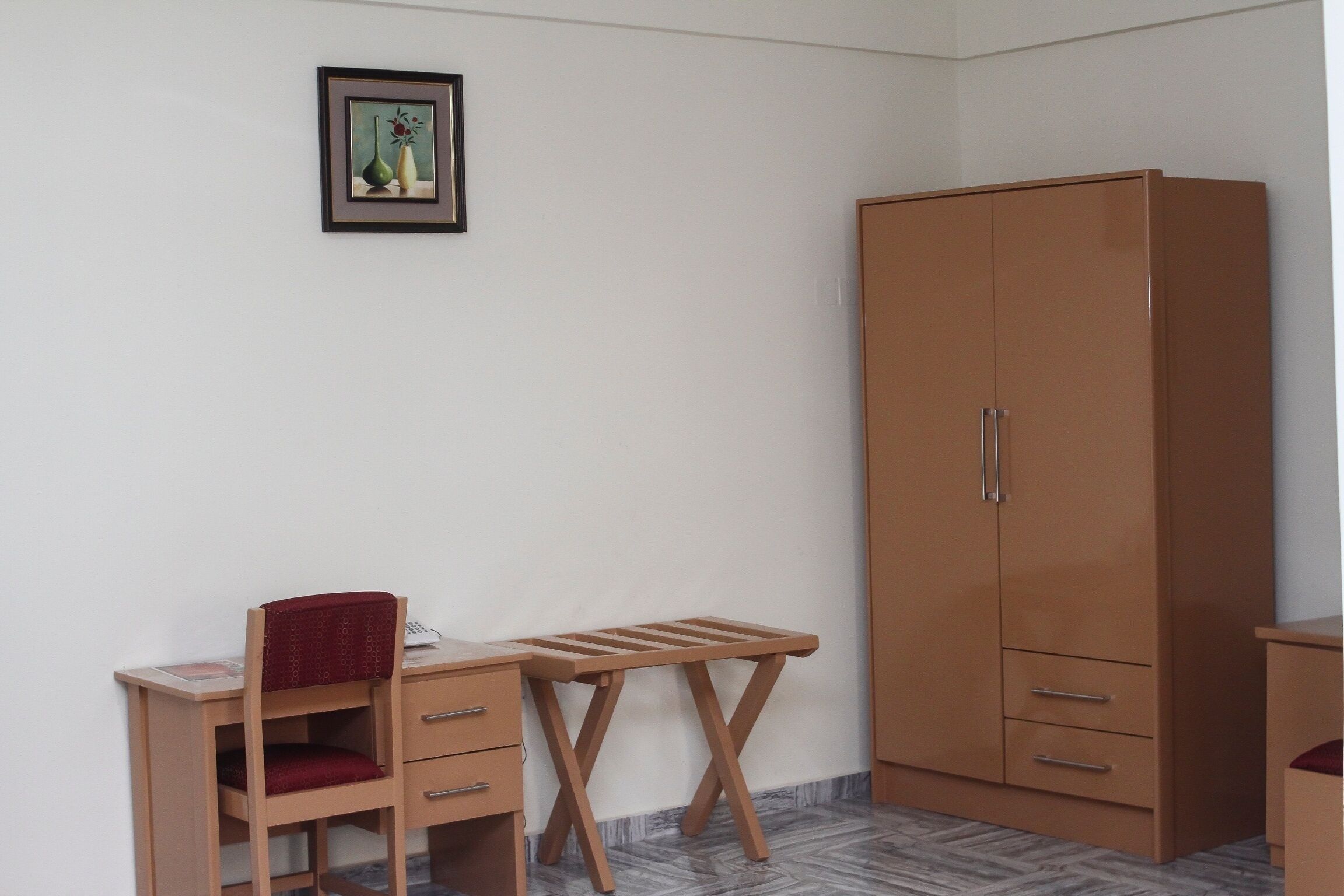 A room with a wooden desk, a chair, a small table, and a wardrobe.