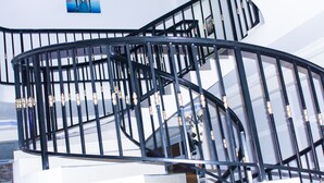 A spiral staircase with black railings and wooden balusters. - Exotic Palace Hotel (Accra)