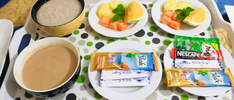 Una bandeja con alimentos para el desayuno, incluyendo fruta, un tazón de sopa y aperitivos envasados.