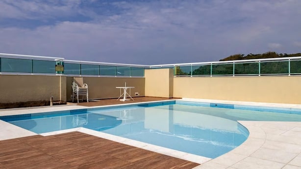 Ein Schwimmbecken mit einer Holzterrasse, einem kleinen Tisch und Stühlen.