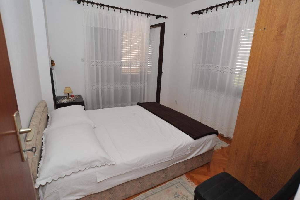 A small, neatly arranged bedroom with a single bed, a nightstand, and a door.