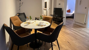 Un coin repas avec une table ronde, quatre chaises et un téléviseur en arrière-plan.