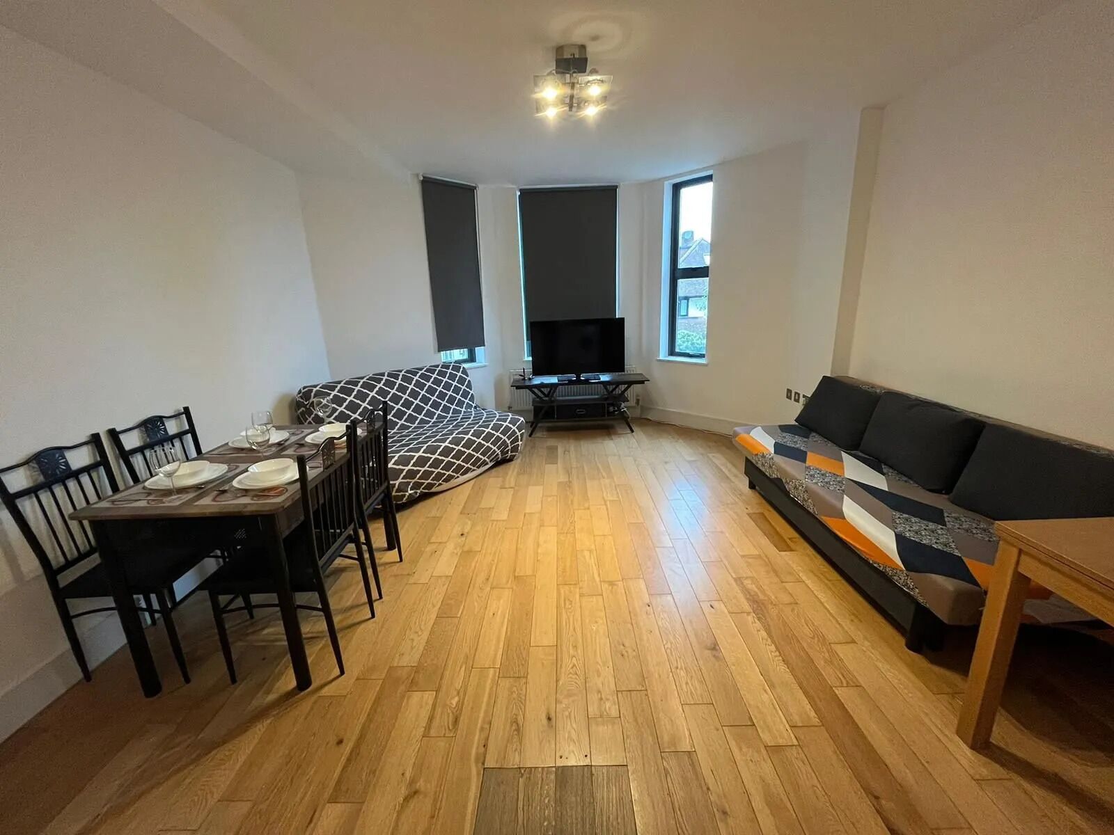 A compact living space with a dining area, a sofa, and a television.