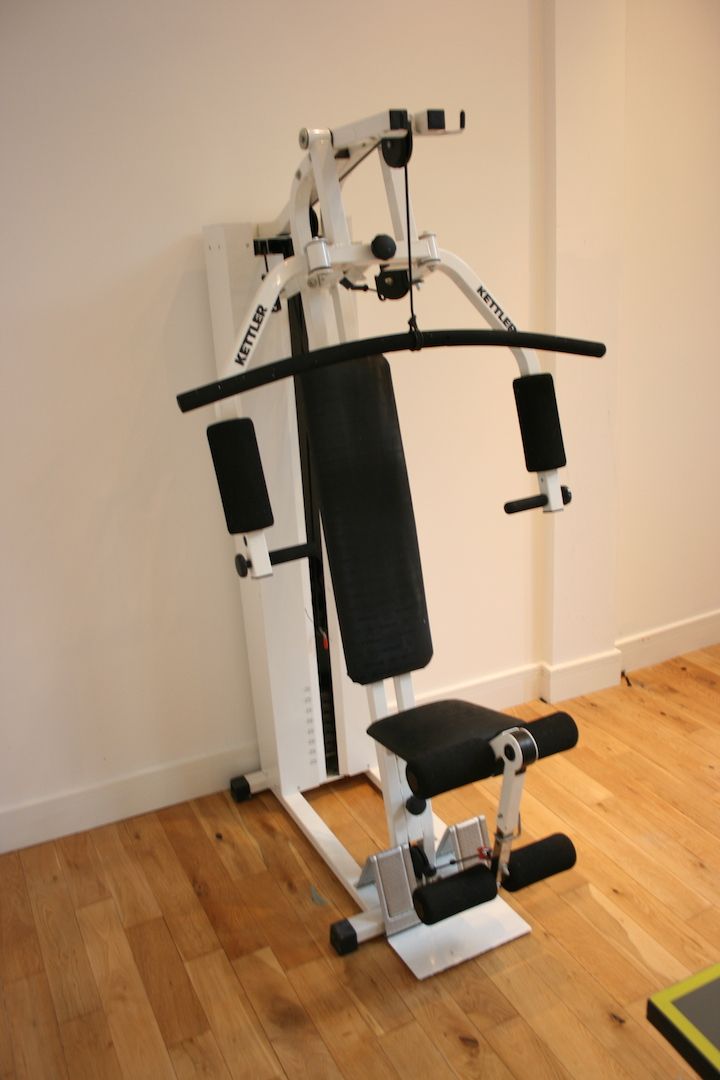 A gym with a bench press and a cable machine.