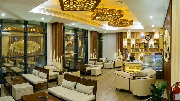 A modern coffee lounge with comfortable seating, a coffee bar, and a variety of coffee and tea displays. - Muscat Gate Hotel (Muscat)