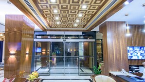 A hotel lobby with a modern design, featuring a patterned ceiling, a reception desk, and a glass entrance. - Muscat Gate Hotel (Muscat)