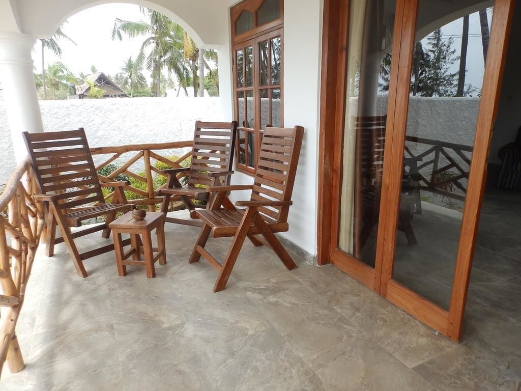 A covered outdoor seating area with wooden furniture and a view of the beach.