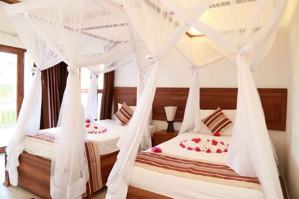 Habitación de hotel con dos camas, cada una con dosel y cabecero de madera.