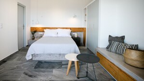 Ein modernes Schlafzimmer mit einem Bett, Nachttischen, einer Bank und einem kleinen Tisch.