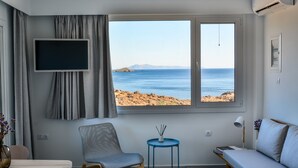 Ein Zimmer mit großem Fenster und Blick auf das Meer und die felsige Landschaft.